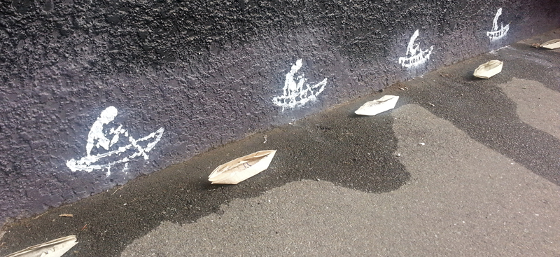 A series of paper boats and drawings on a wall.
