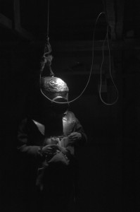 A person wearing a diving helmet in a dark room.